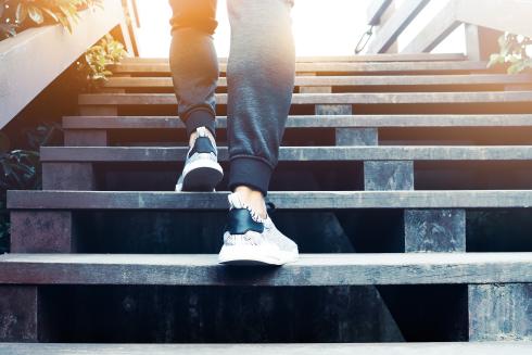 A person outside walking up a wooden staircase.